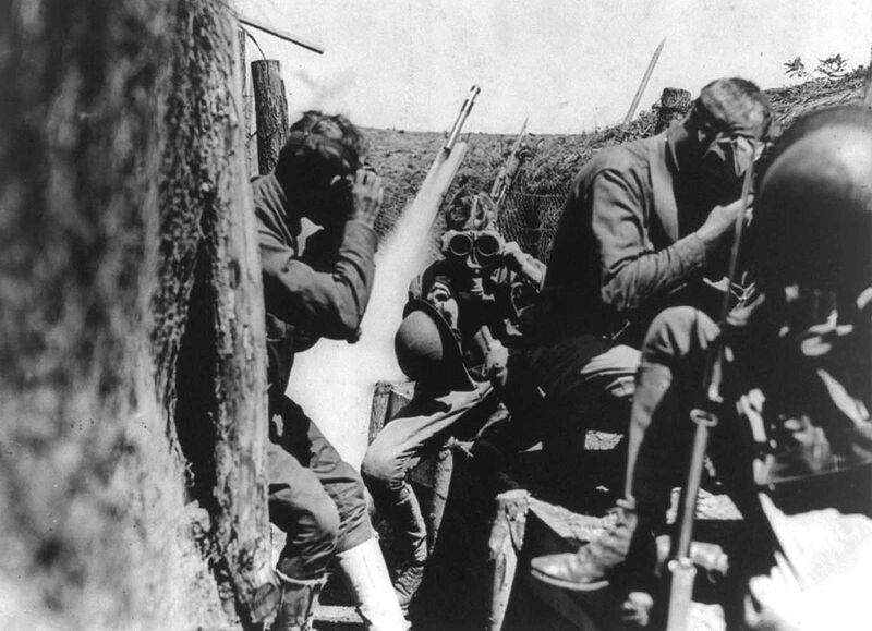 U.S. soldiers in trench putting on gas masks. Behind them, a signal rocket appears to be in mid-launch. When gas attacks were detected, alarms used included gongs and signal rockets.