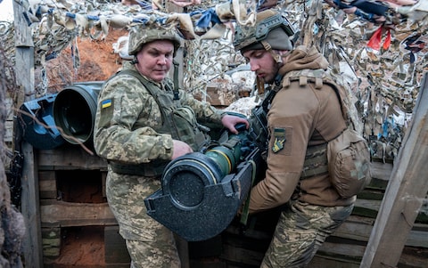 Ukrainian soldiers handle a British-manufactured NLAW anti-tank weapon on the frontlines