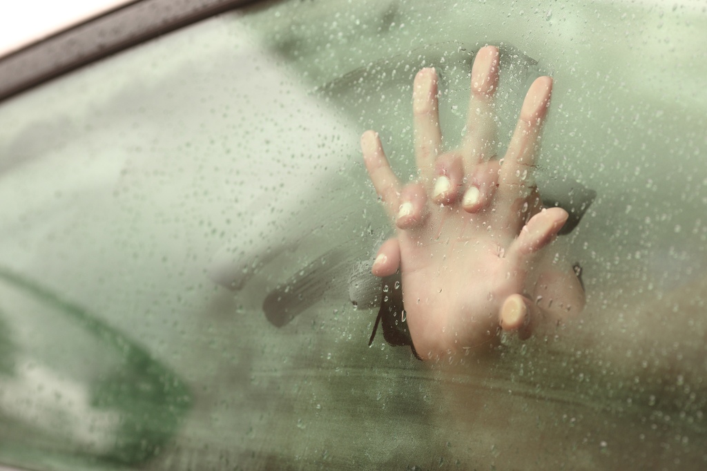 Couple pressing hands against steamy car window